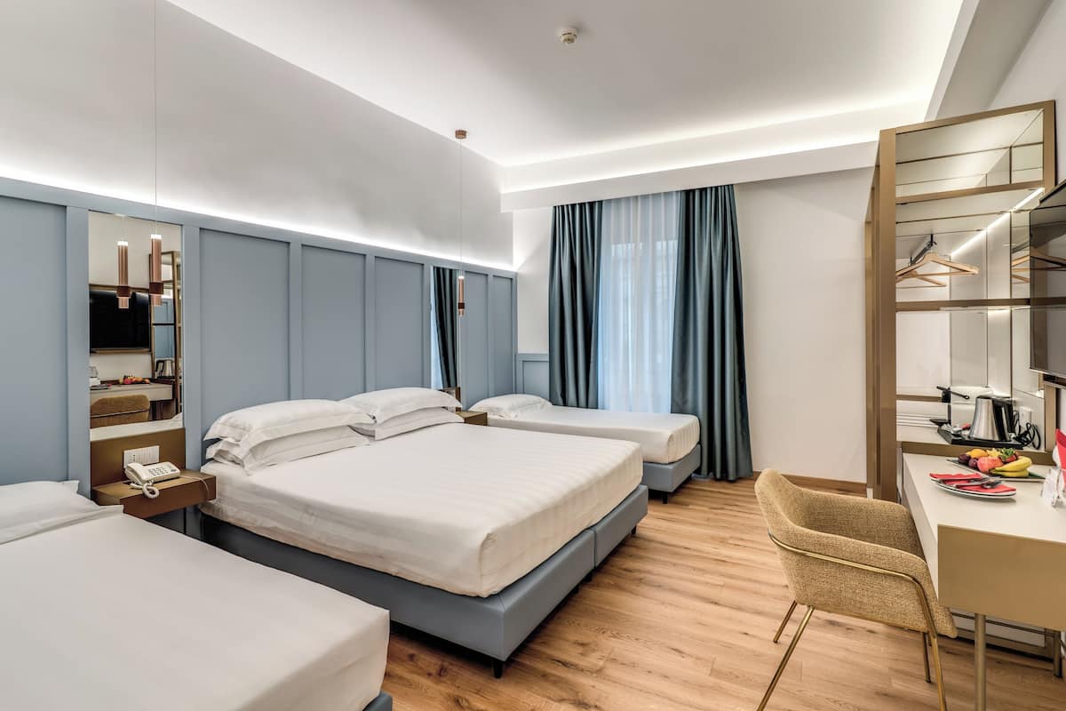 Una habitación de hotel con dos camas, un escritorio, una silla, un espejo y un armario.