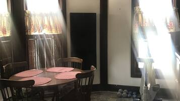 A dining area with a round table, four chairs, and a large window with curtains.