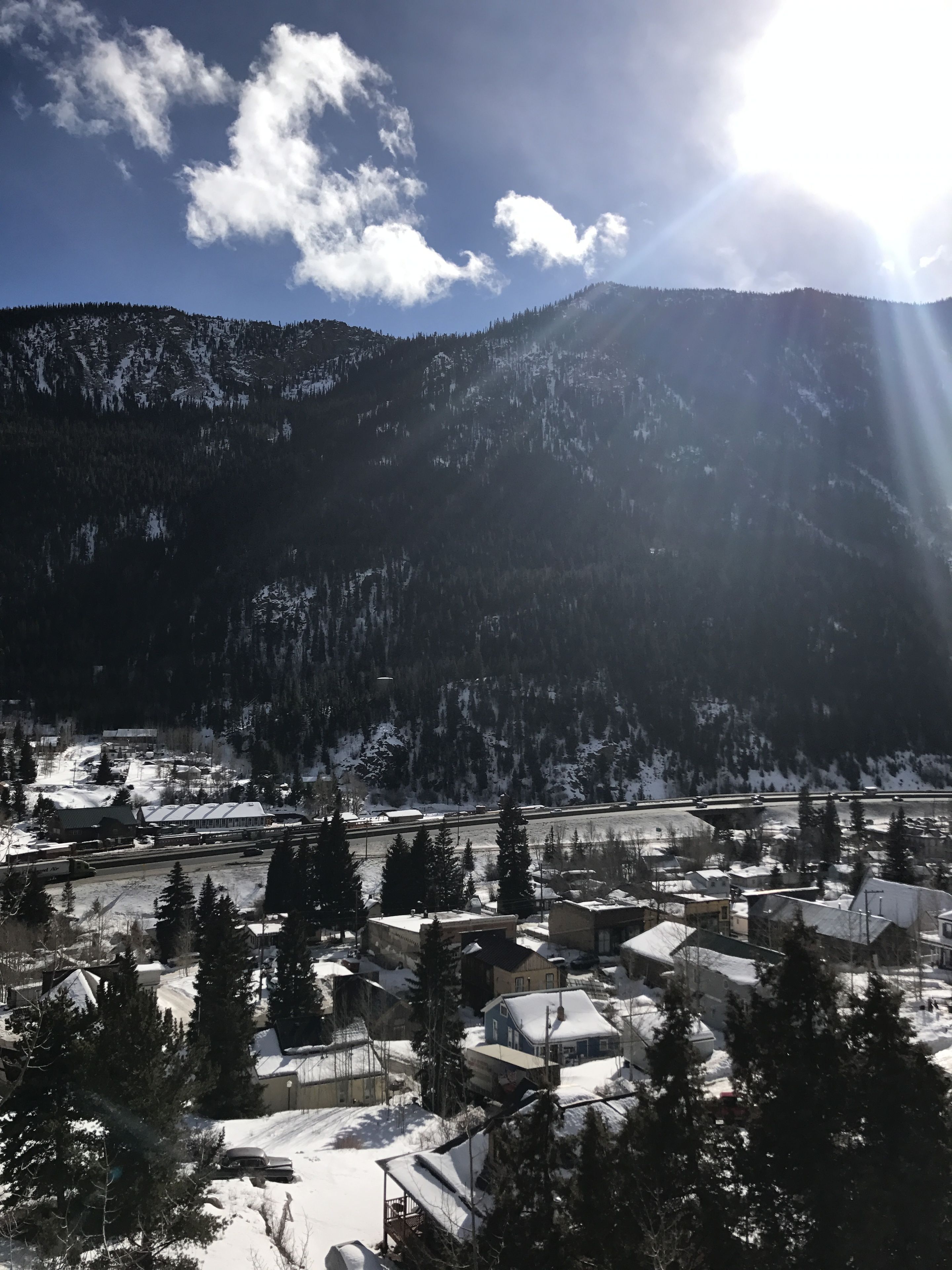 Un pueblo cubierto de nieve con edificios y árboles, rodeado de montañas.