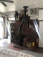 Una estufa de leña en una sala de estar con una escalera y una chimenea.