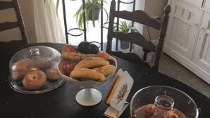 A dining table with a variety of baked goods, including donuts and muffins, covered with glass domes. - Historic Windsor Hotel (Silver Plume)