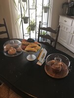 Una mesa de comedor con una variedad de productos horneados, como donas y muffins, cubiertos con campanas de cristal.