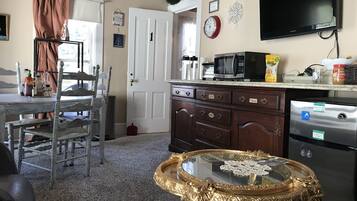 A kitchen with a dining area, a TV mounted on the wall, and a refrigerator.