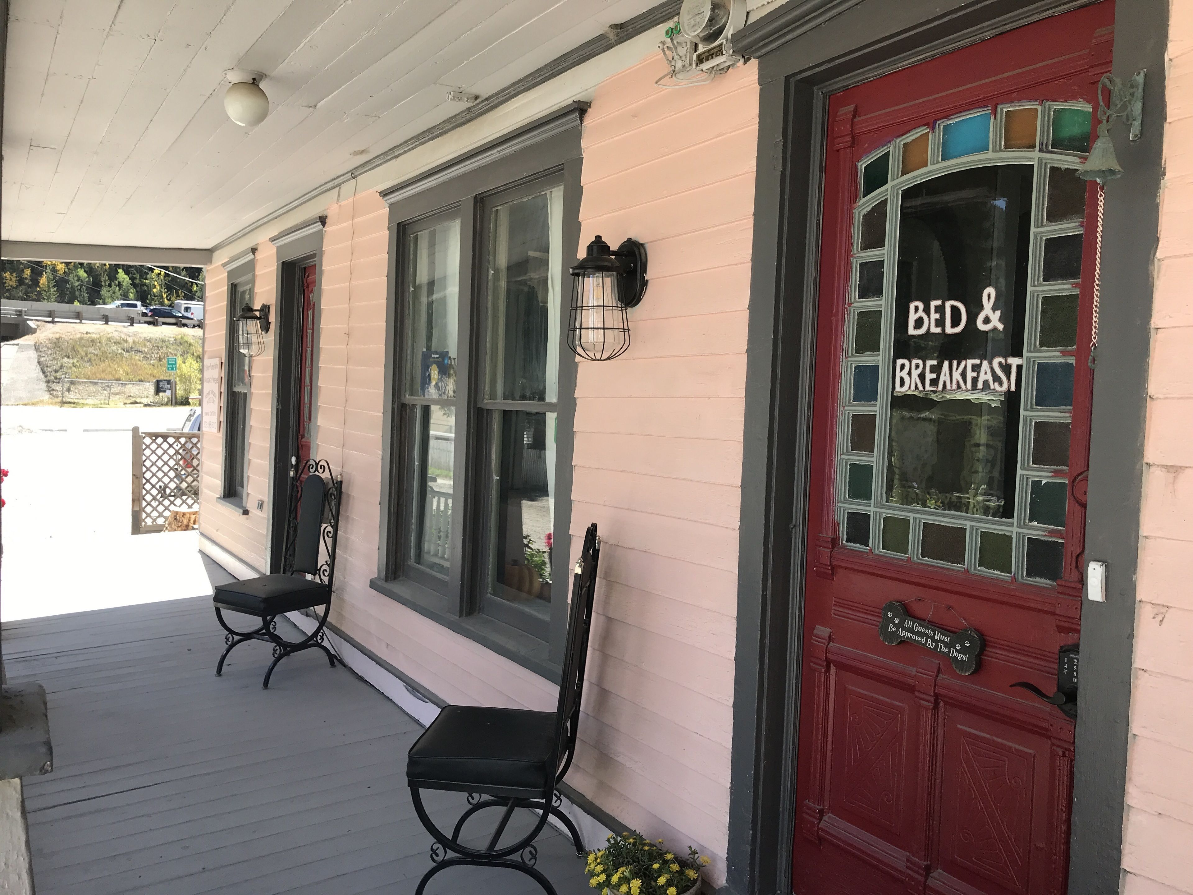 A building with a red door labeled "BED & BREAKFAST" and a sign stating "All Guests Must Be Approved By The Dogs!".