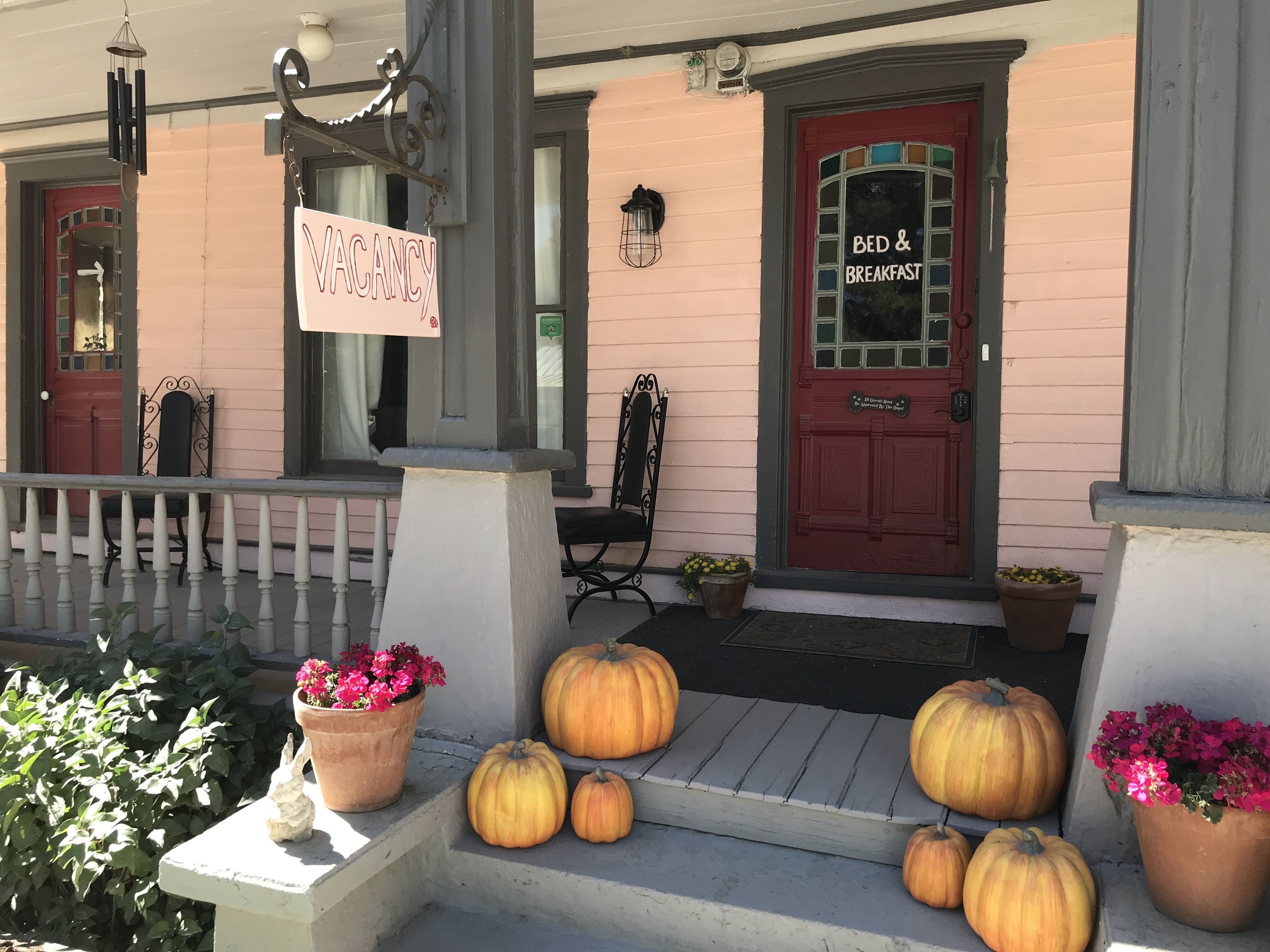 A building with a 'VACANCY' sign, a 'BED & BREAKFAST' sign, and several pumpkins on the porch.