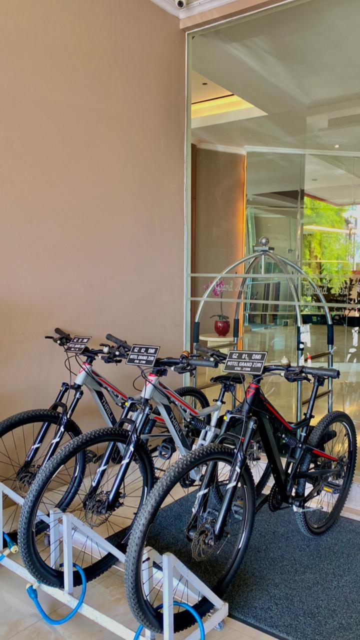 Un aparcamiento para bicicletas con tres bicicletas estacionadas frente a un edificio con puerta de vidrio.