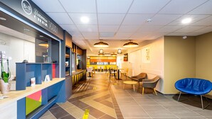 Zona de recepción de un hotel con mostrador, asientos y vista despejada del comedor al fondo.