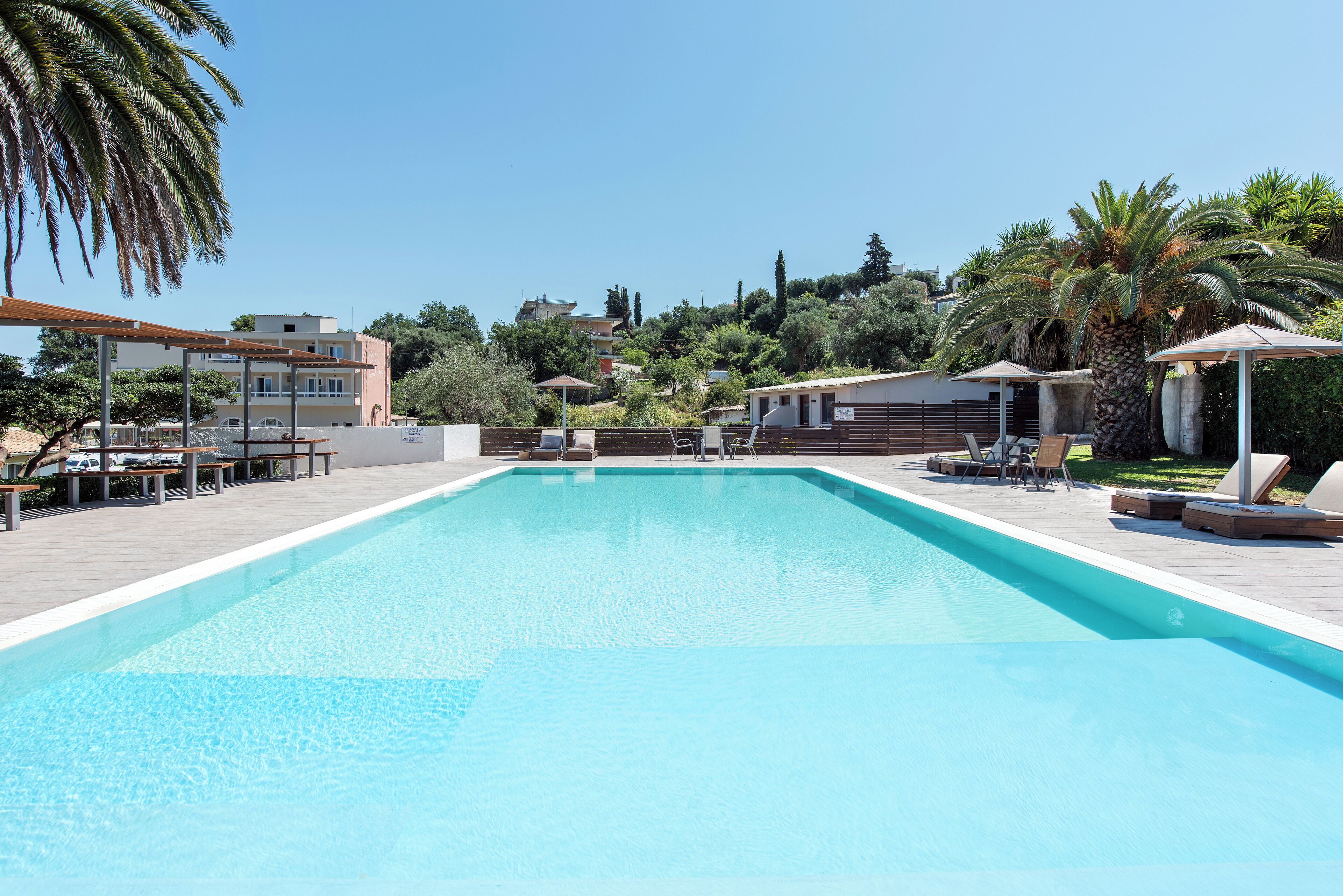 Una piscina rettangolare con bordo piastrellato, circondata da lettini e ombrelloni.