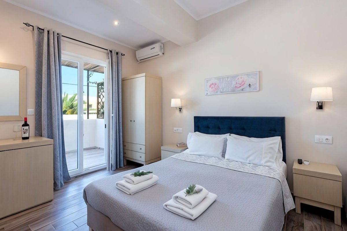 A hotel room with a bed, a nightstand, a wardrobe, a sliding glass door to the balcony, and a wall-mounted air conditioner.