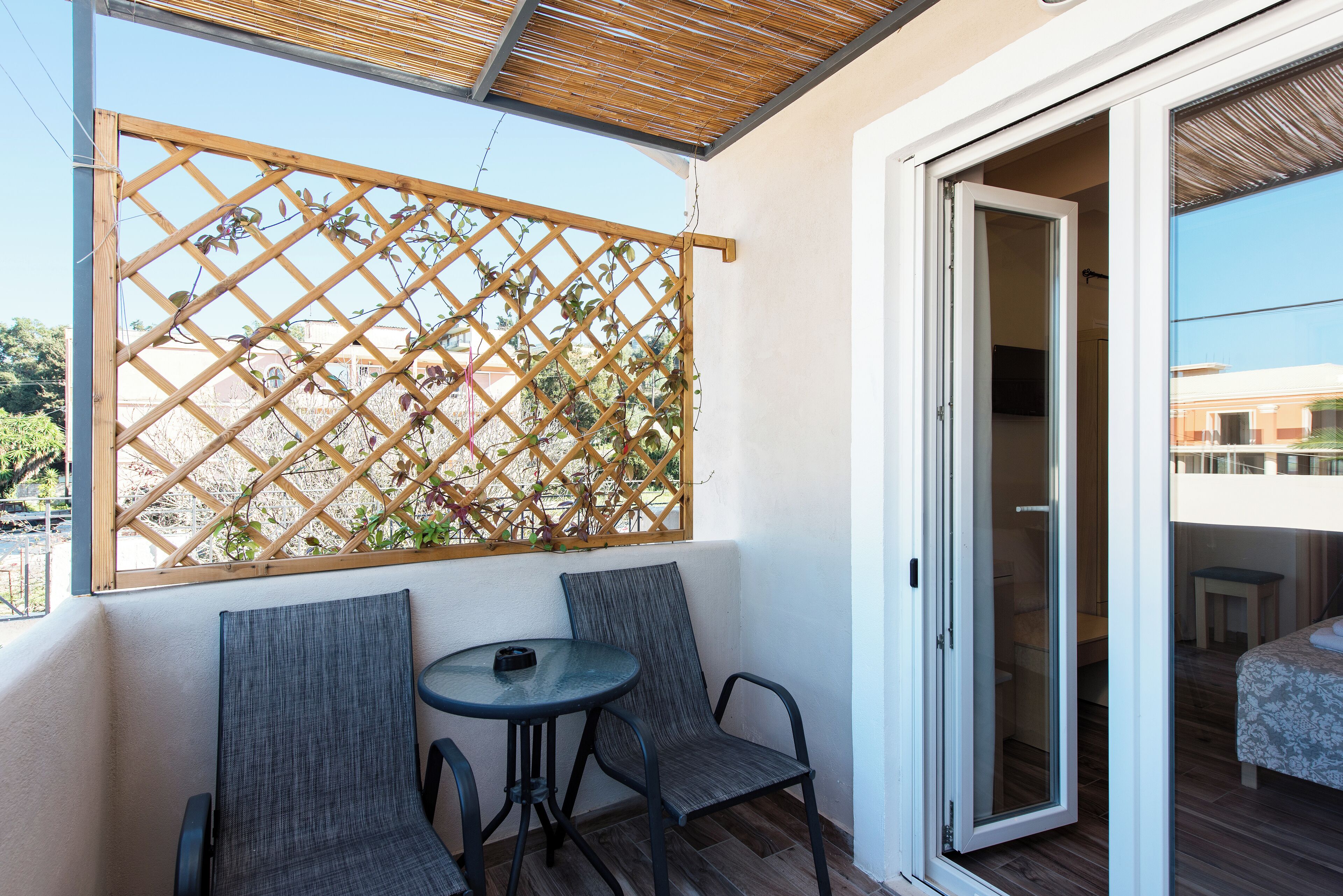 A balcony with a wooden lattice screen, two chairs, and a small table.