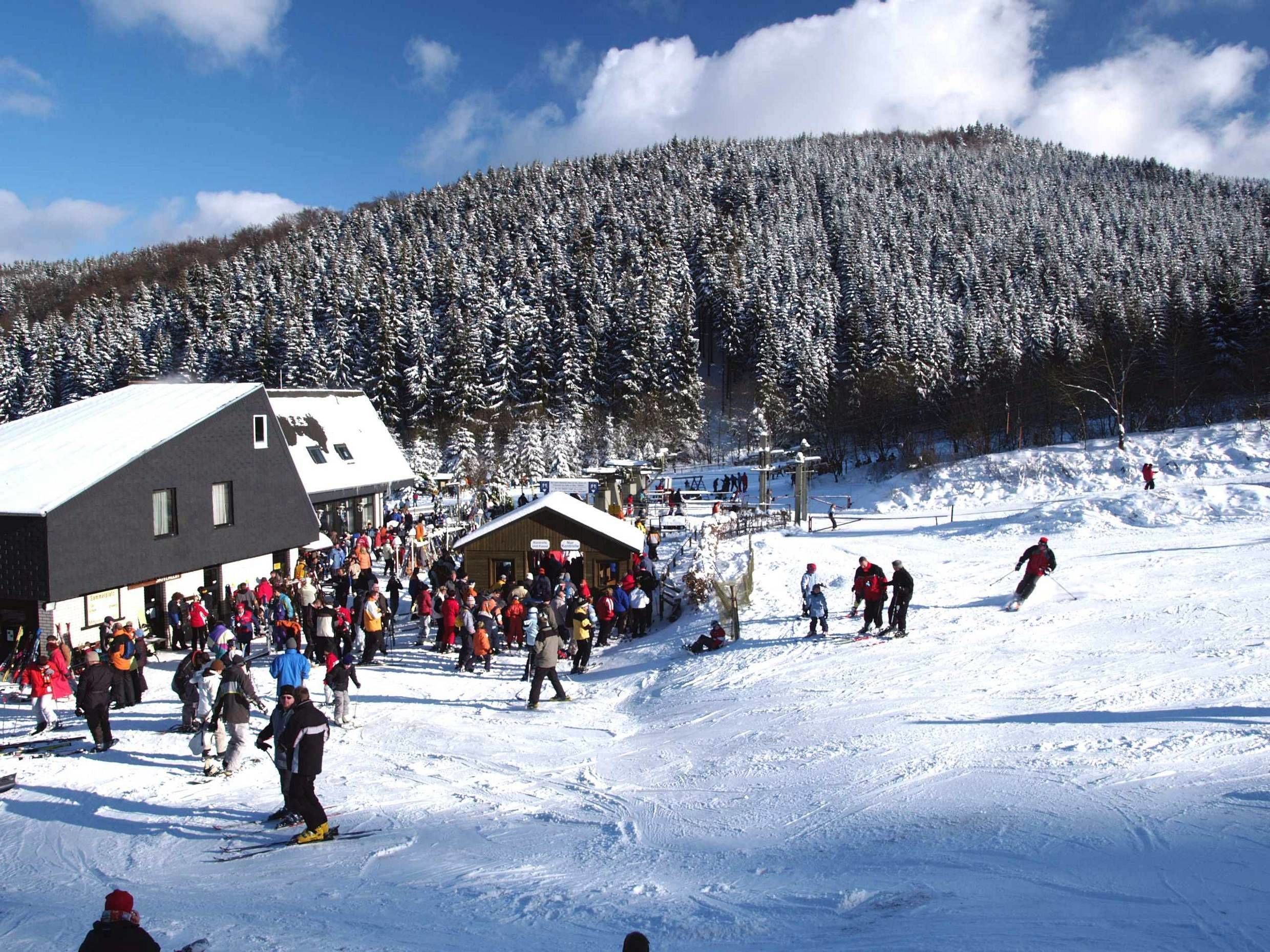 A ski resort with a large building and a crowd of people.