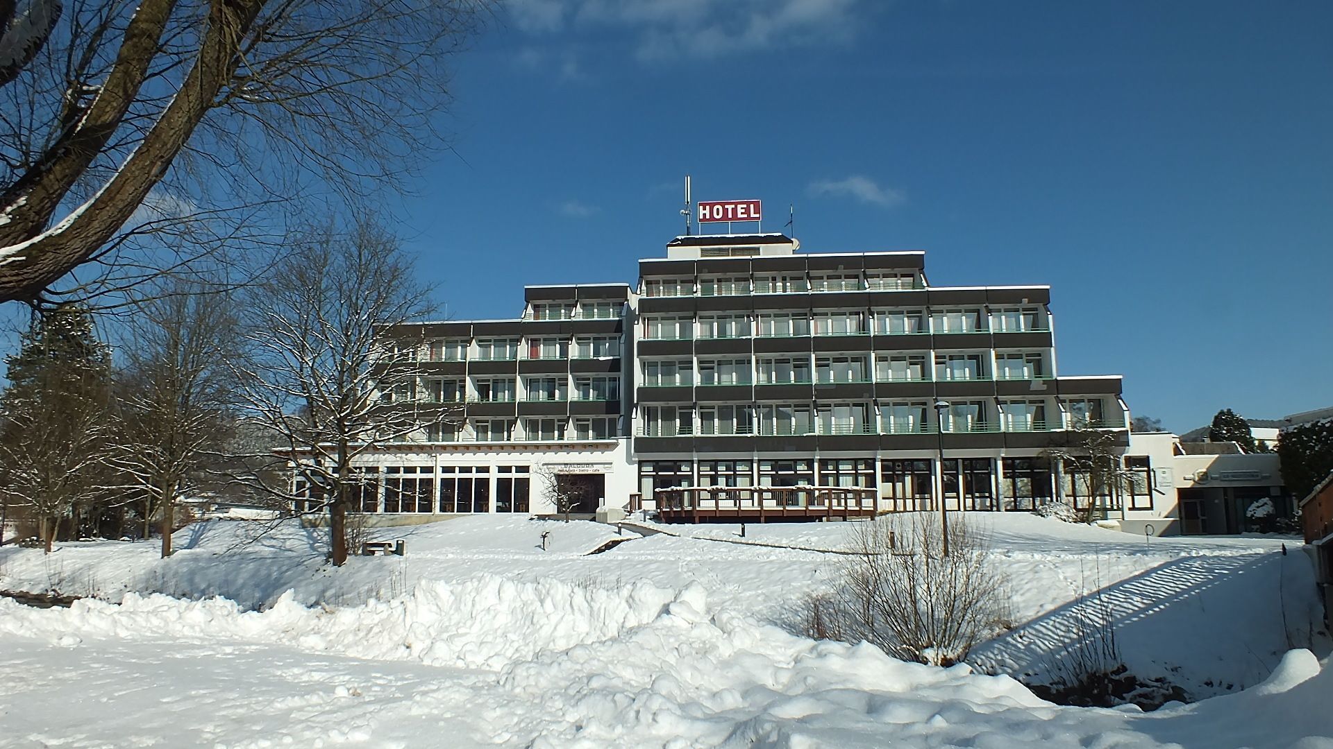 Un hôtel à plusieurs étages, surmonté d’une grande enseigne « HÔTEL », qui présente une architecture moderne avec de grandes fenêtres et un toit plat.