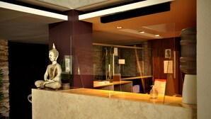 A statue of a seated figure on a counter, a water dispenser, and a glass partition.