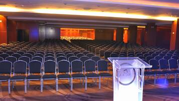 Uma sala de conferências com fileiras de cadeiras e um púlpito.