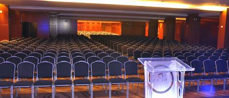 A conference room with rows of chairs and a podium.