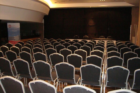 Un salón de conferencias con filas de sillas orientadas hacia un escenario.