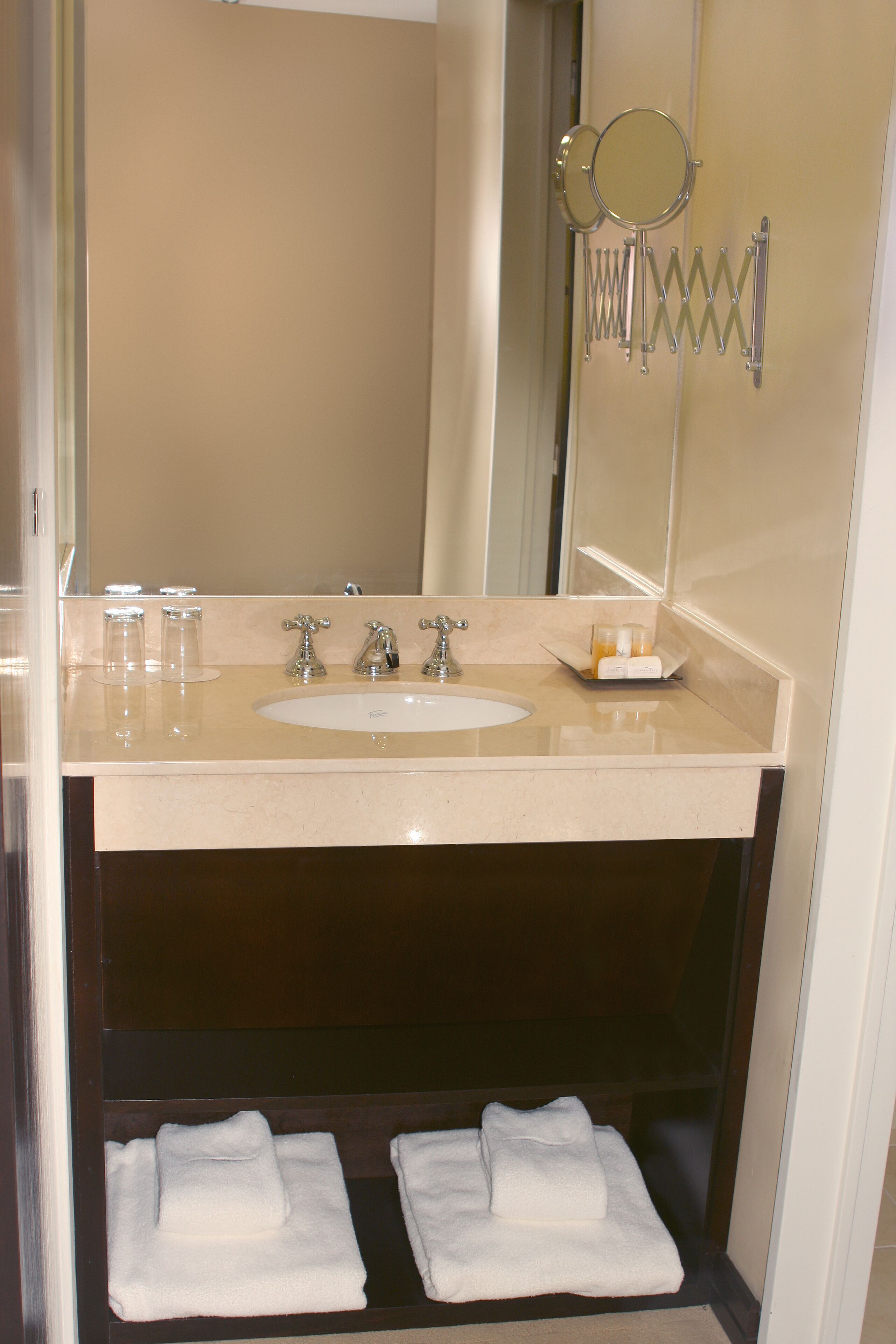 A bathroom with a sink, two mirrors, and a towel rack.