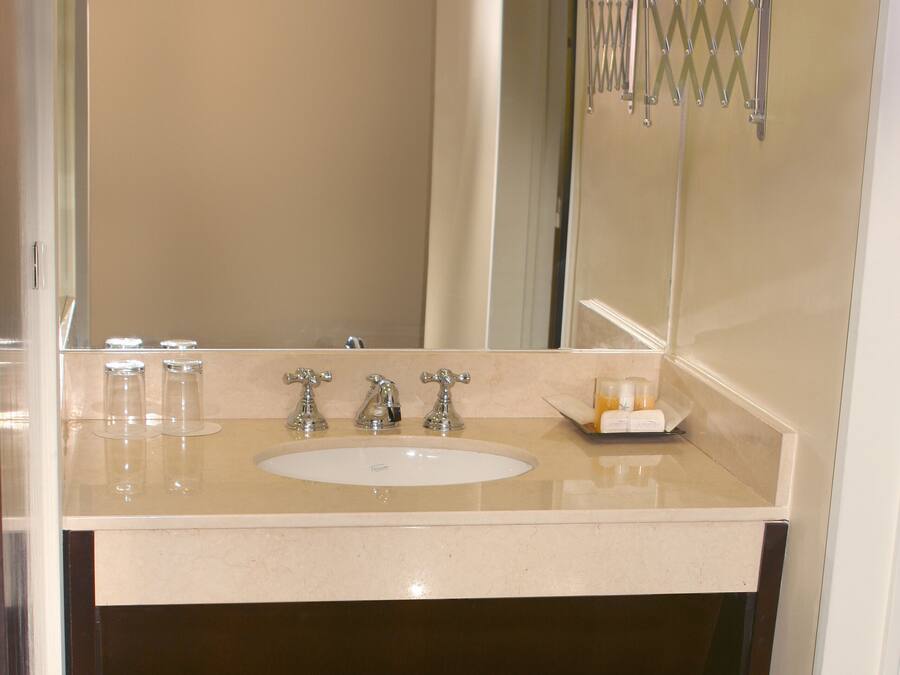 A bathroom with a sink, two mirrors, and a towel rack.