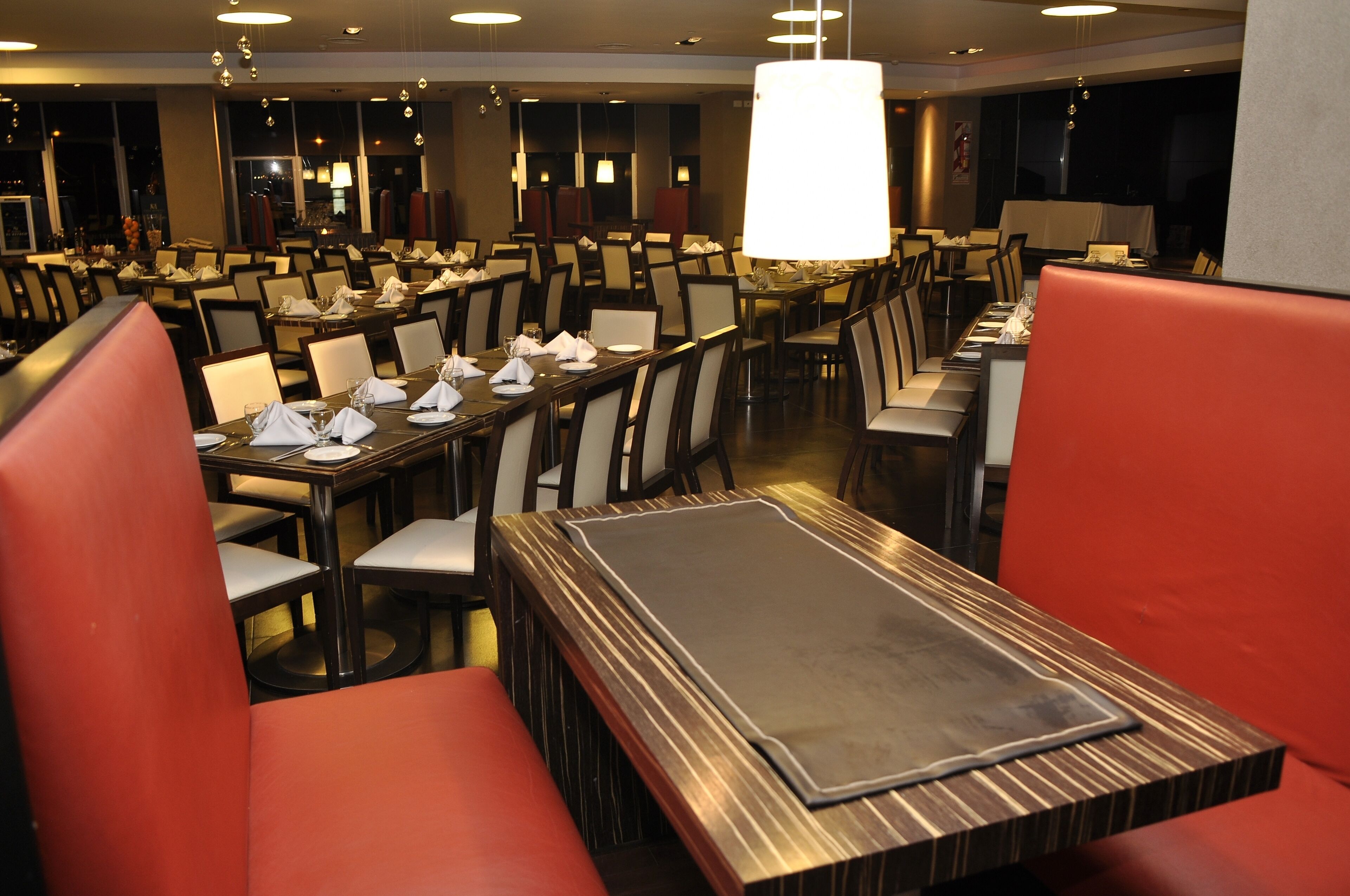 Un restaurante con varias mesas y cabinas, cada una con servilletas y platos blancos.