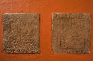 Two stone plaques with inscriptions on an orange wall.