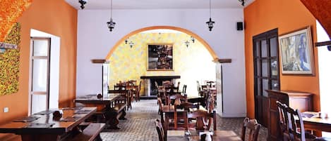 Un restaurante con mesas y sillas de madera, un arco de entrada y suelo de baldosas.