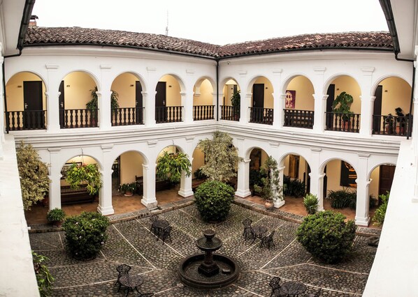 A courtyard with a fountain, stone flooring, and multiple arches. - Hotel La Plazuela (Popayán)