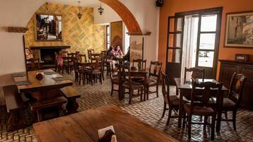 Un restaurant avec des tables et des chaises en bois, un sol en briques et un grand miroir au mur.