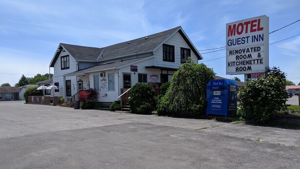 A motel with a sign indicating renovated rooms and a kitchenette. - Guest Inn (Quinte West)