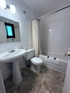 A bathroom with a white sink, toilet, and bathtub. There is a shower curtain and a towel rack.