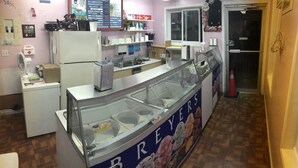 A bakery counter with a display case for ice cream, a refrigerator, and various bakery items on shelves. - Guest Inn (Quinte West)