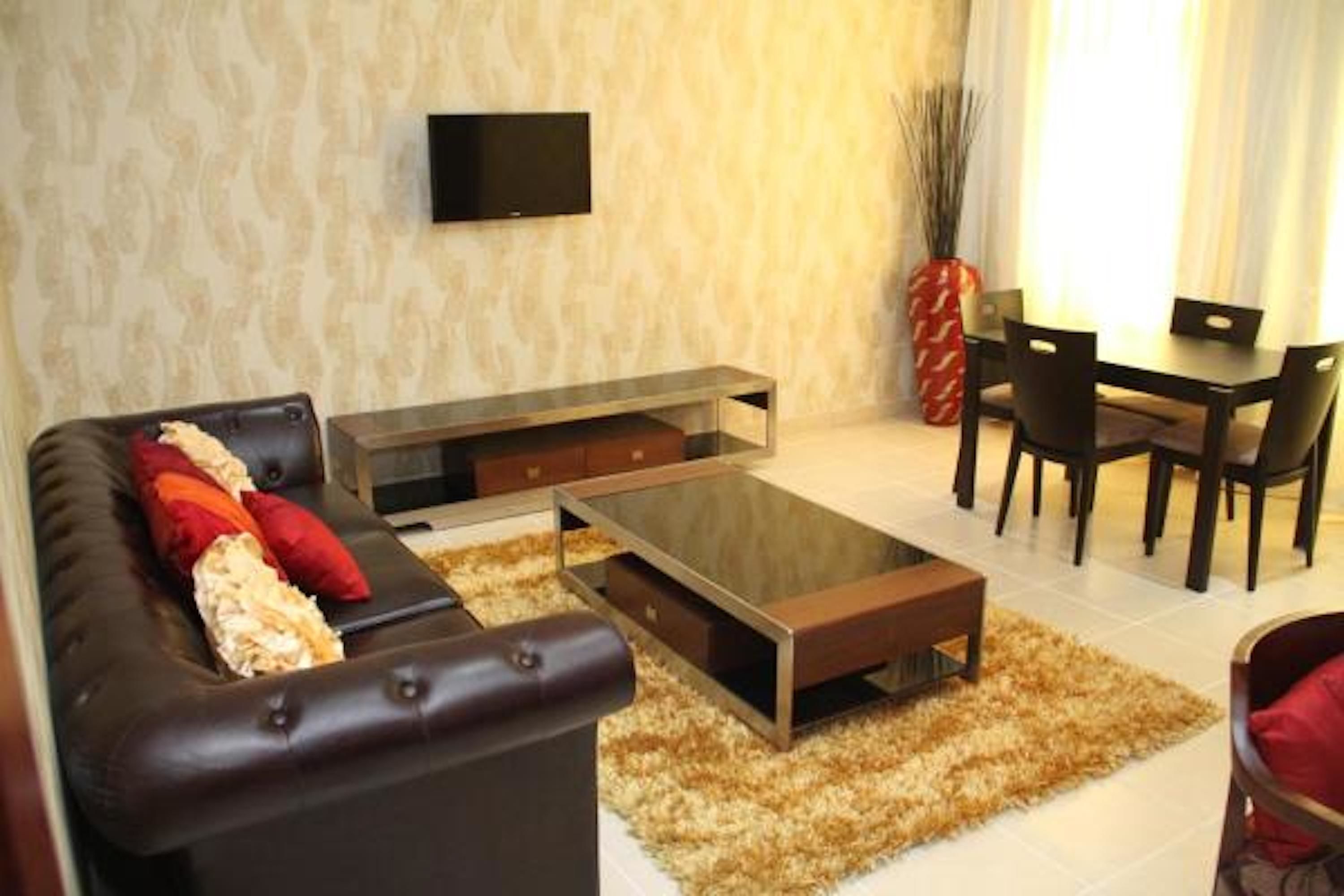 A living room with a sofa, coffee table, TV, dining table, chairs, and a vase.