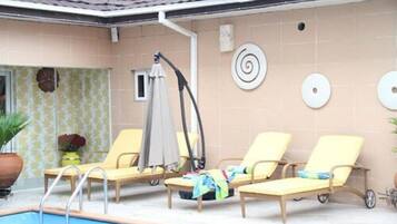 Un espace piscine avec des chaises longues et une fontaine.