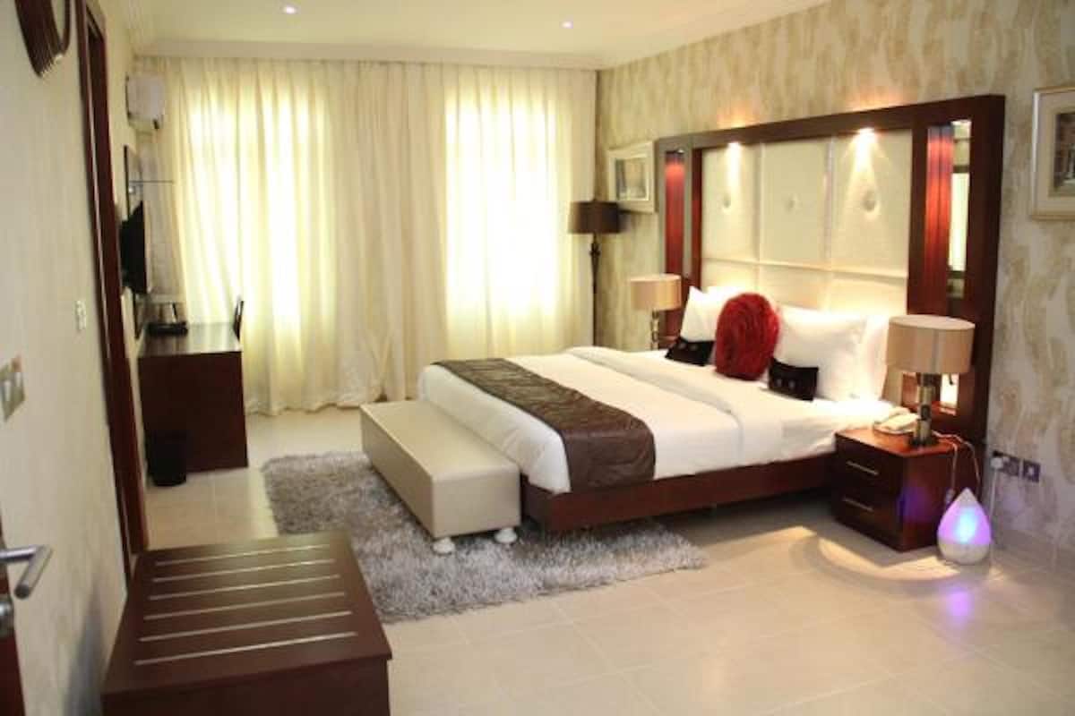 Ein Hotelzimmer mit einem großen Bett, Nachttischen, einem Schreibtisch und einem Stuhl.