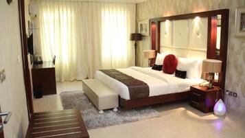 Une chambre d’hôtel avec un grand lit, des tables de chevet, un bureau et une chaise.