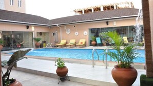 A pool area with lounge chairs, a water feature, and potted plants. - Palazzo Dumont Hotel (Lekki)