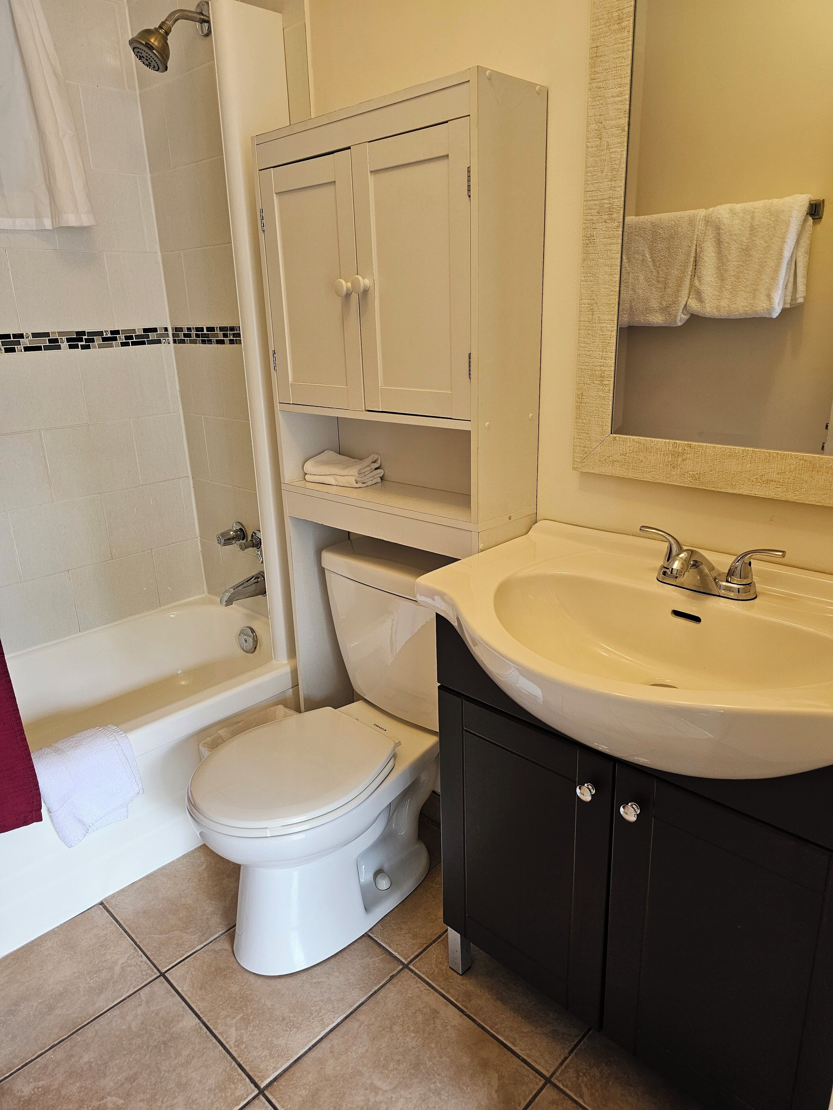 Un baño con bañera, inodoro, tocador y espejo.