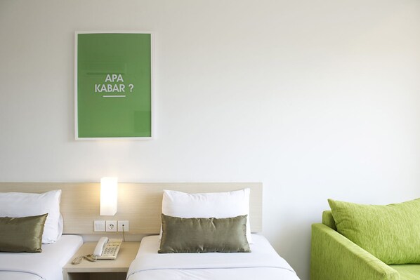 A hotel room with two beds, a green wall art with text, a bedside lamp, a phone, and a green armchair. - Zuri Express Hotel Pekanbaru (Pekanbaru)