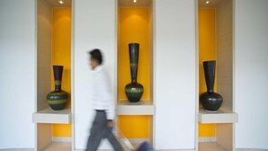 Un intérieur moderne avec trois vases disposés sur des étagères, le tout sur un mur jaune.