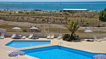 Una piscina al aire libre de temporada, sombrillas