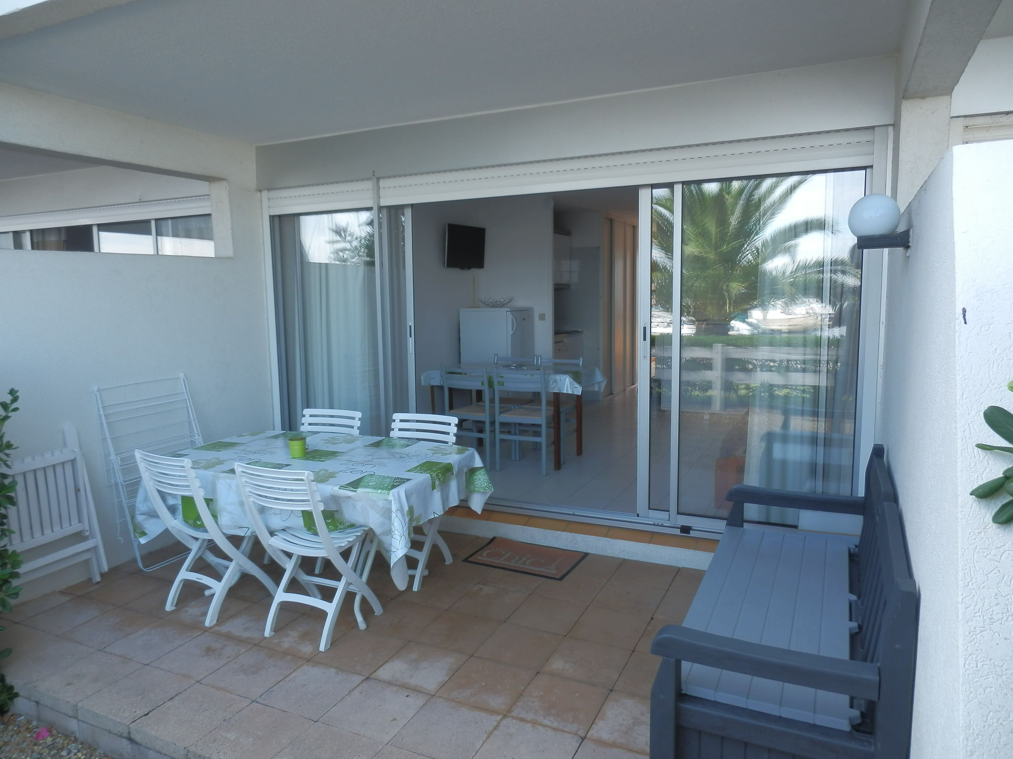 Une terrasse avec une table et des chaises, une porte-fenêtre coulissante et une vue sur l’extérieur.