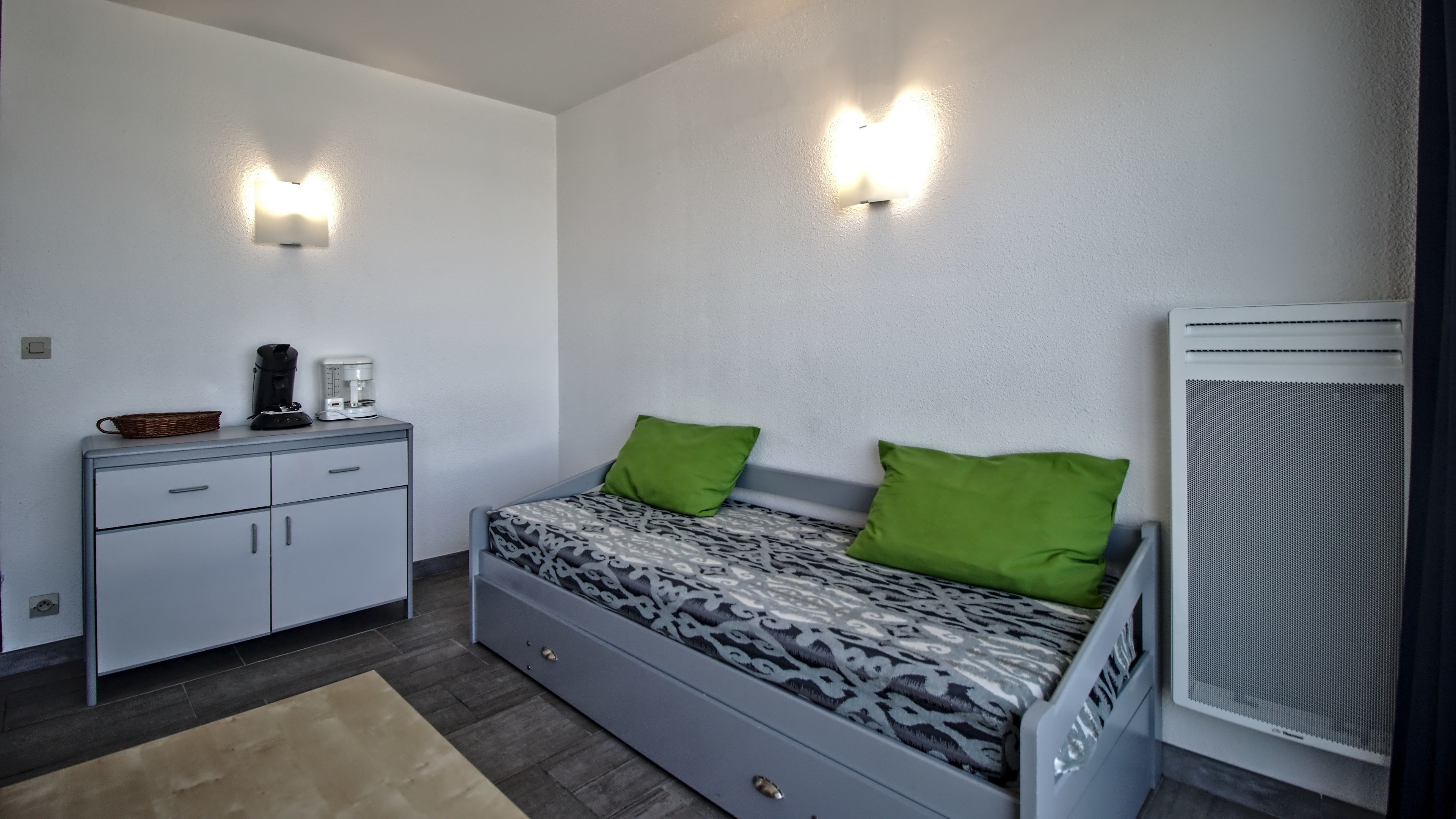 Un dormitorio con una cama, un aparador, una cafetera y un calentador.