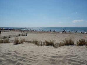 A sandy beach with a wooden fence and people in the distance. - Les Rivages d'Ulysse (Le Grau-Du-Roi)