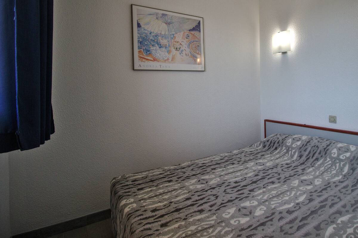 Ein Schlafzimmer mit einem Bett, einer Wandleuchte und einem gerahmten Bild.
