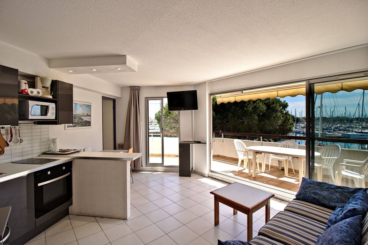 Eine moderne Wohnung mit Küche, Essbereich und einem Balkon mit Blick auf den Hafen.