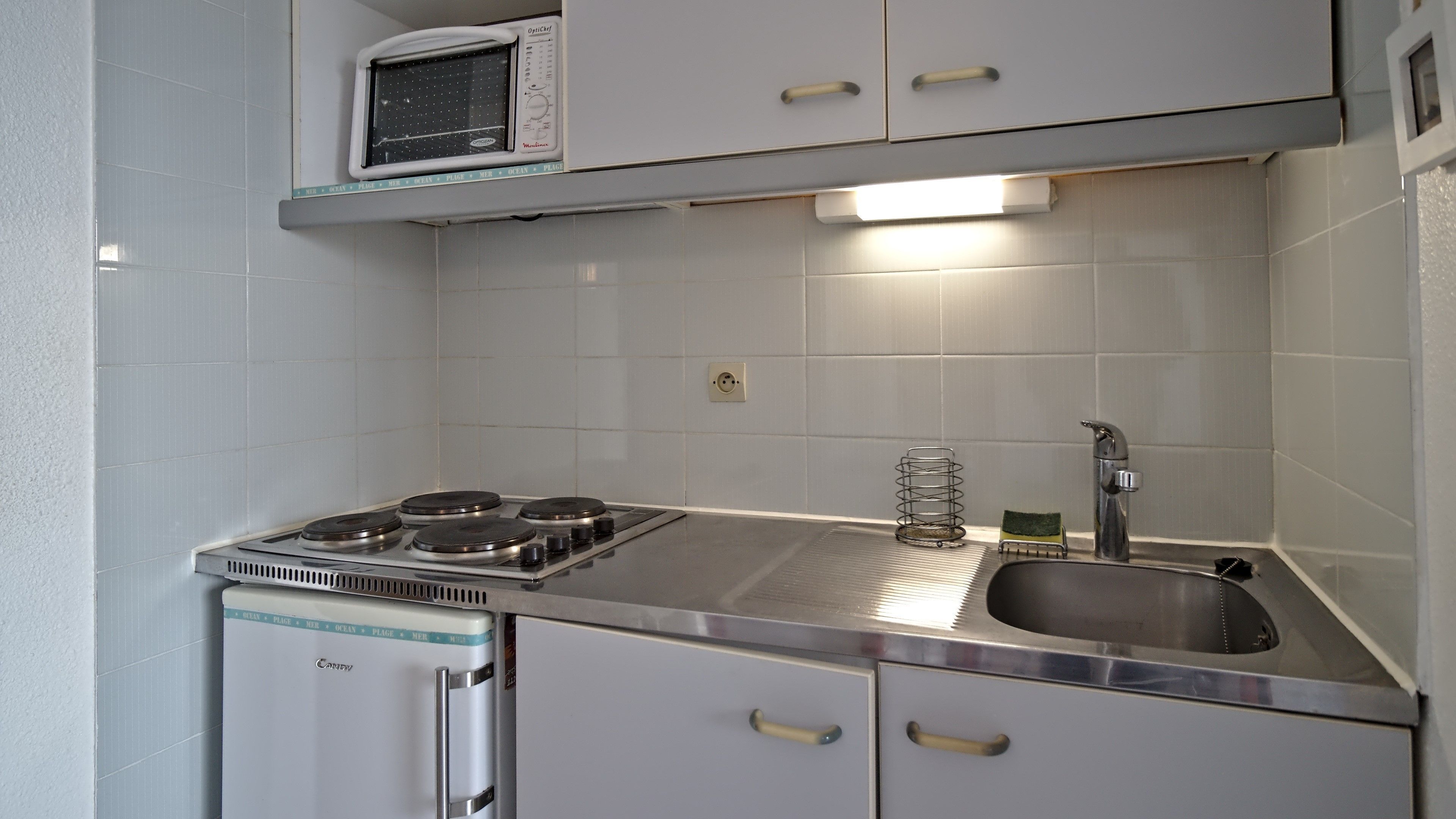 A compact kitchen with a built-in microwave, a gas stove, and a sink.