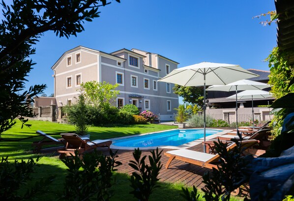 Una piscina al aire libre, sombrillas, tumbonas