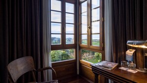 A room with a wooden desk, a chair, and a large window with curtains.