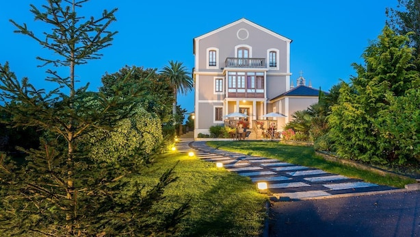A two-story building with a balcony, surrounded by lush greenery and a well-maintained garden.
