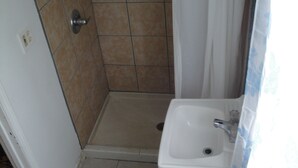 Ein kleines Badezimmer mit Dusche, Waschbecken und Toilette.