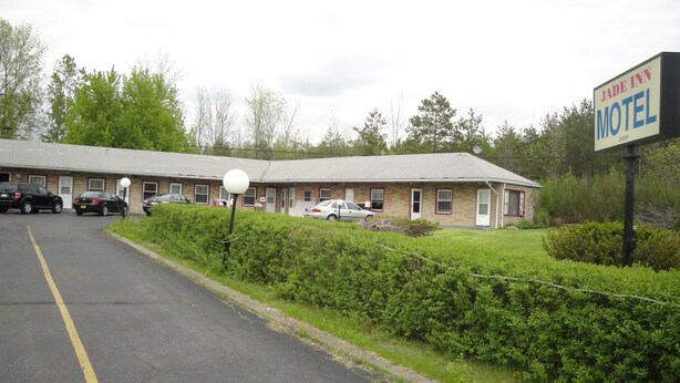 Ein Motel mit Ziegelbau, mehreren Zimmern und einem Parkplatz.